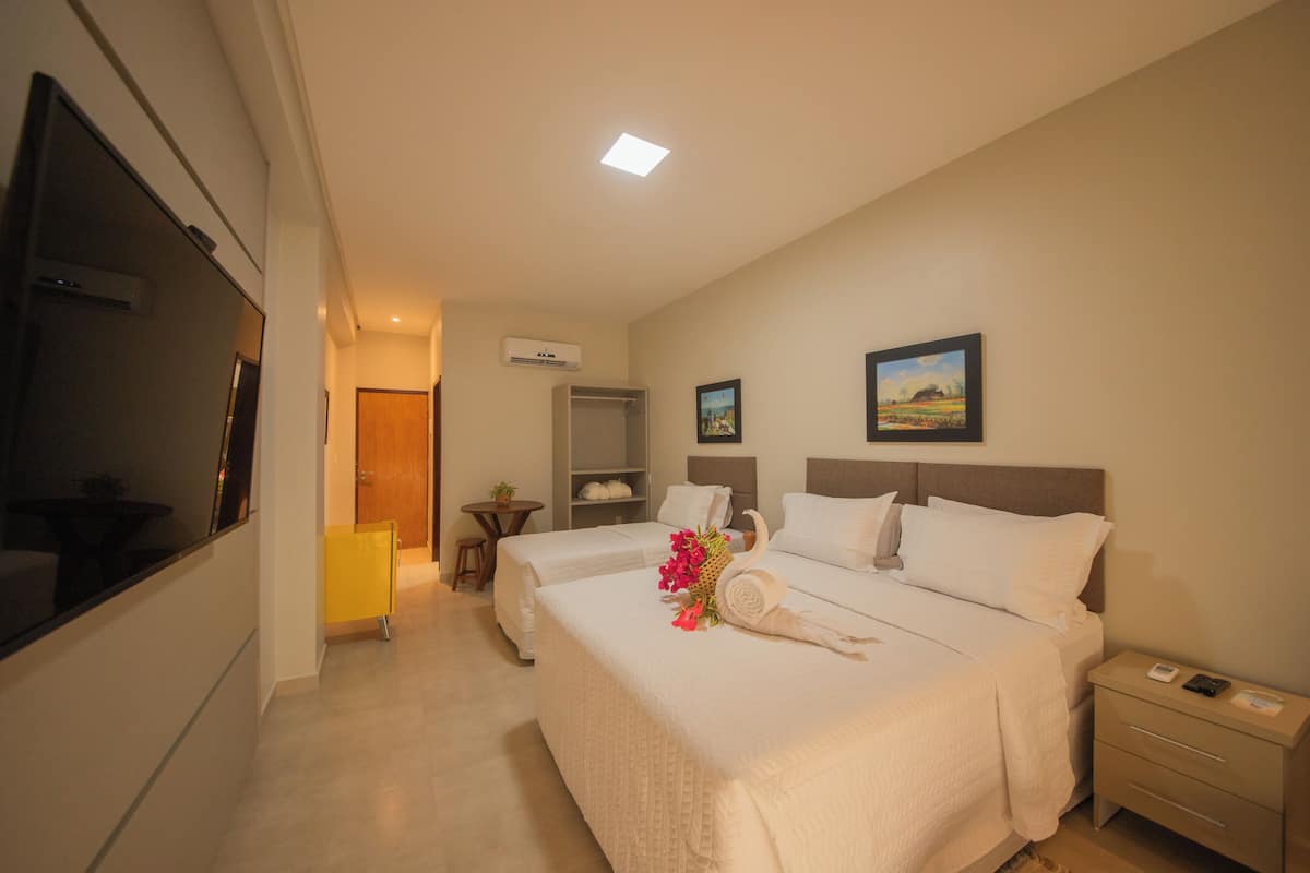A hotel room with two beds, a TV, a bedside table, a nightstand, and a painting on the wall.