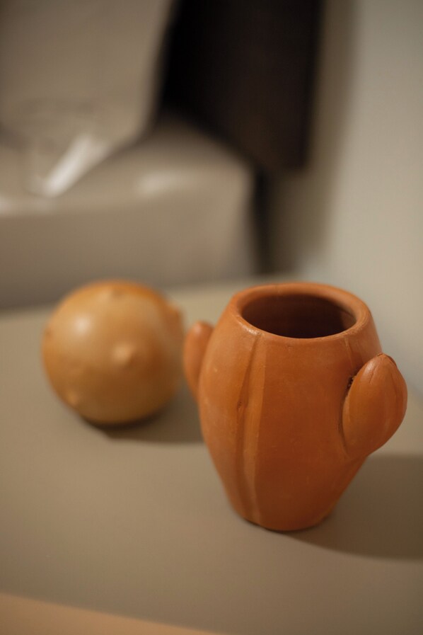 A small terracotta pot and a spherical object on a table. - Obi Exclusive Pousada (Maragogi)