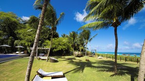 A tropical resort with palm trees, a pool, lounge chairs, and a view of the ocean. - Obi Exclusive Pousada (Maragogi)