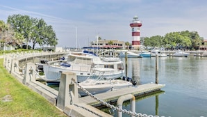 A marina with boats docked, a lighthouse in the background, and a building with a sign. - Sunset Rentals- 1687 Bluff Villas (Hilton Head Island)