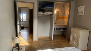 A bedroom with a bed, a nightstand, a lamp, a wardrobe, and a bathroom visible through an open door. - Village house near the lake (Codolet)