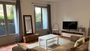 A living room with a brown sofa, a white coffee table, a TV, and a large window with curtains. - Village house near the lake (Codolet)
