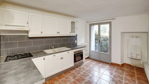 A kitchen with white cabinets, a gas stove, a sink, and a window with a view. - Village house near the lake (Codolet)