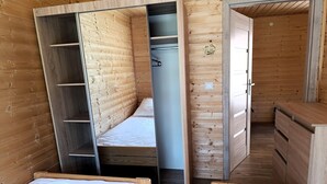 Une petite pièce en bois comprenant un lit, une armoire et un petit bureau.