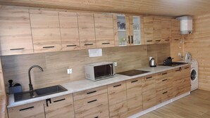 Une cuisine moderne avec des meubles en bois, un four à micro-ondes encastré, un évier et un lave-linge.