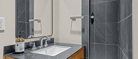 A bathroom with a marble sink, wooden cabinet, and a mirror.