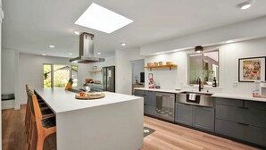 Una cocina moderna con una isla central, electrodomésticos integrados y un amplio ventanal que proporciona luz natural.