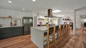 Una cocina moderna con una isla central, sillas de madera y un comedor con mesa.