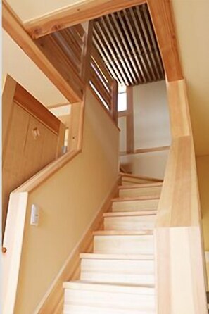 Una escalera de madera con barandilla y una lámpara fijada a la pared.