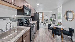 Een moderne keuken met roestvrijstalen apparatuur, een granieten aanrecht en een eethoek met een ronde tafel en stoelen.