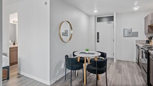 Een moderne keuken met een inbouwoven en een eethoek met een ronde tafel en stoelen.