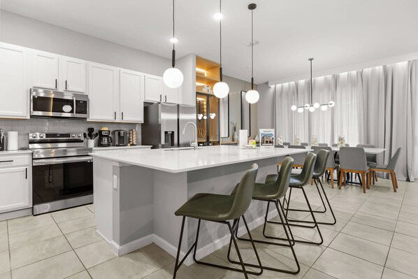 A modern kitchen with white cabinets, stainless steel appliances, and a central island with bar stools.