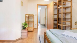 A bedroom with a bed, wooden shelving unit, a small plant, and a hallway leading to another room. - Central, quiet oasis with garden and parking lot (Graz)