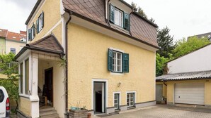 A two-story house with a tiled driveway, a garage, and a small porch area. - Central, quiet oasis with garden and parking lot (Graz)