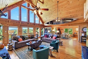 A spacious cabin interior with a high ceiling, large windows, a dining area, and a cozy seating area. - Hot Tub, Views, Fire Pit, Game Room, Super Nice! - The Lodge at Pinnacle Ridge (Lake Lure)