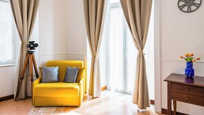 A bright room with a yellow sofa, a tripod, and a vase with flowers. - La Casa di Famiglia by Napoliapartments (Naples)