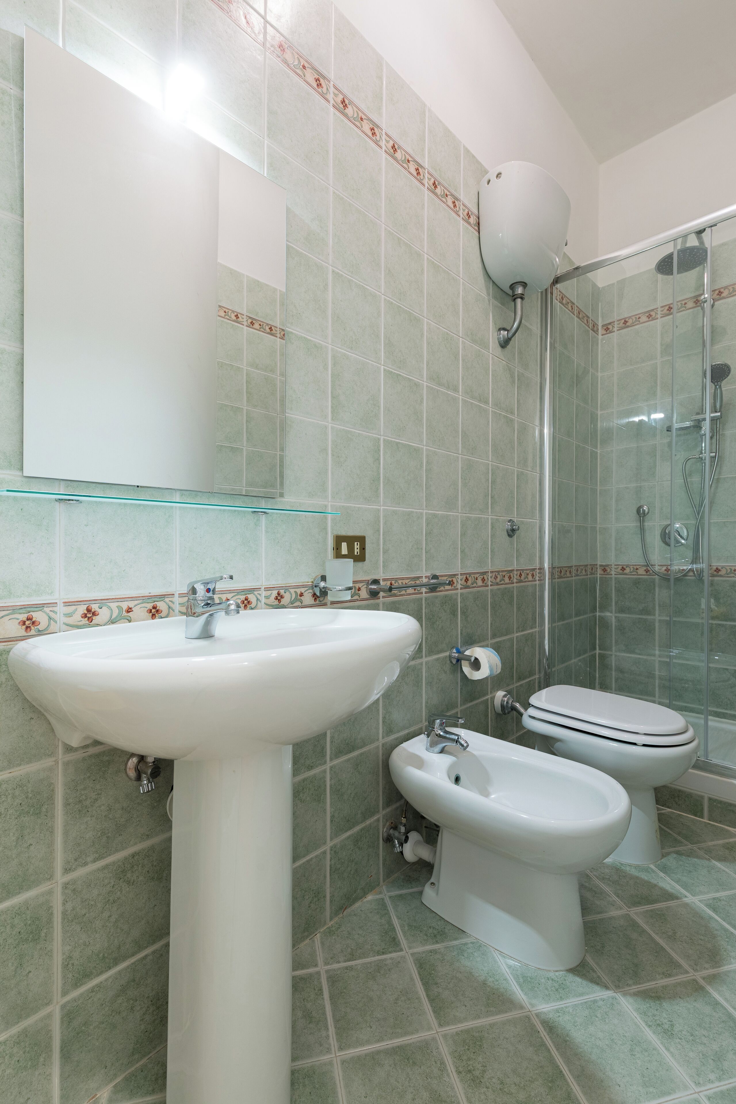 Un baño con lavamanos, bidé, inodoro y cabina de ducha de vidrio.