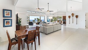 Un amplio espacio habitable con mesa de comedor, sofá y ventiladores de techo.