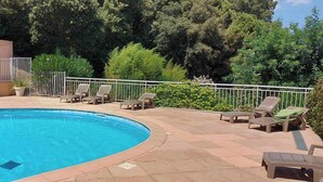 A swimming pool with lounge chairs and a metal fence.