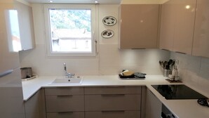 A modern kitchen with a window, a sink, a stove, and cabinets.