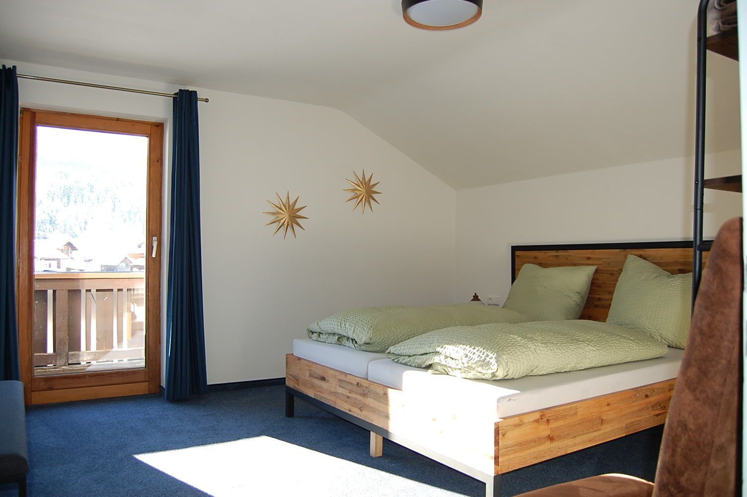 A bedroom with a wooden bed, a balcony, and a star decoration on the wall.