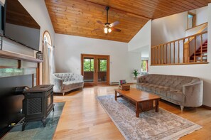 A spacious living room with a fireplace, a sofa, a coffee table, and a ceiling fan.