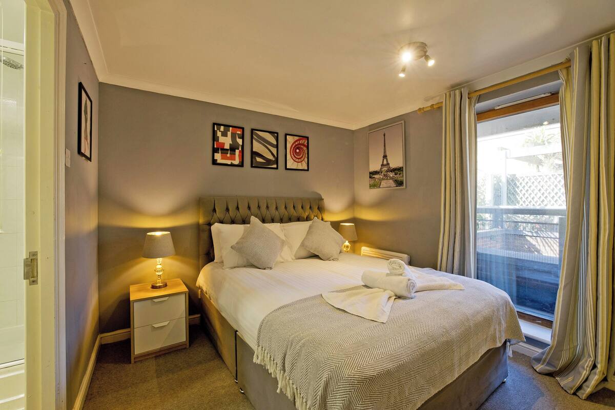 A neatly arranged bedroom with a bed, bedside tables, and a window with curtains.