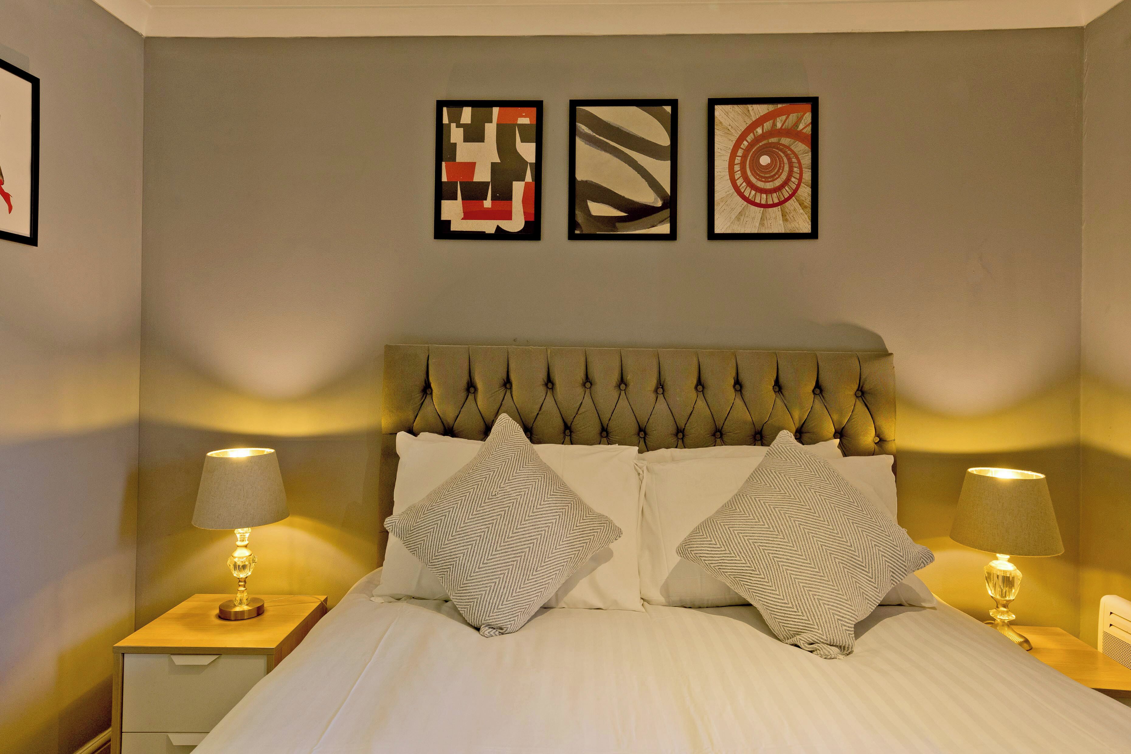 A neatly made bed with two pillows, a headboard, and two bedside lamps.