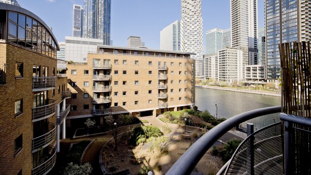 A multi-story building with a brick facade, multiple balconies, and a river view. - Imperial Meridian Place Apartment (London)