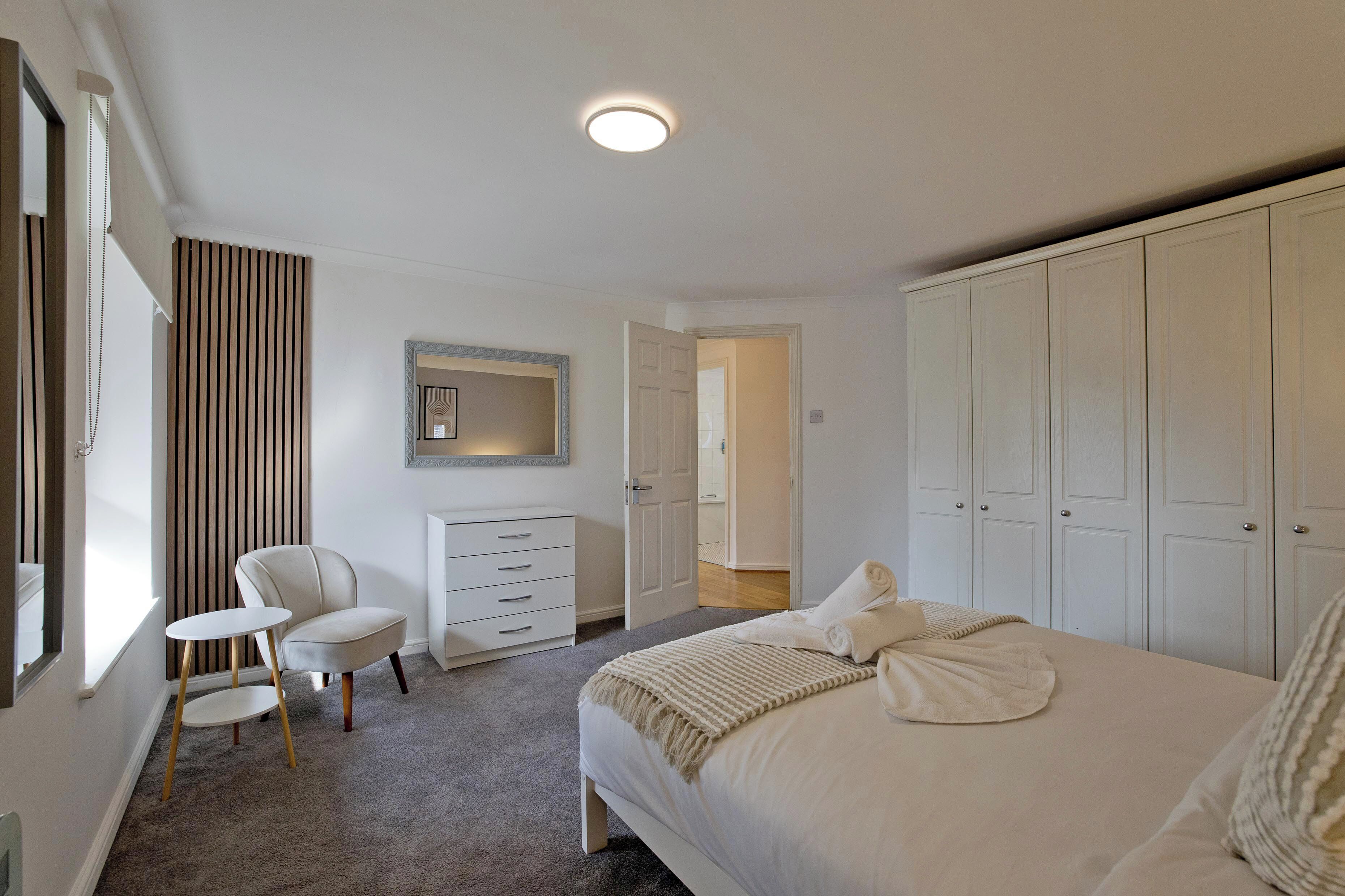 A bedroom with a bed, a chair, a dresser, and a wardrobe.