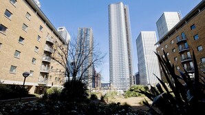 A high-rise building with a modern design, surrounded by other buildings and some greenery. - Imperial Meridian Place Apartment (London)