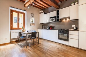 Une cuisine moderne avec des meubles blancs, un plafond en bois et un coin repas comprenant une table et des chaises.