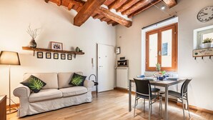 A cozy living room with a sofa, a dining table, and a kitchen area. - Porta Romana Charme Flat - Florence Dolce Vita (Florence)