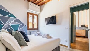 A bedroom with a bed, pillows, a TV, and a view of another room. - Porta Romana Charme Flat - Florence Dolce Vita (Florence)