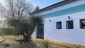 Una casa blanca con detalles azules, un árbol en el jardín delantero y tres ventanas.