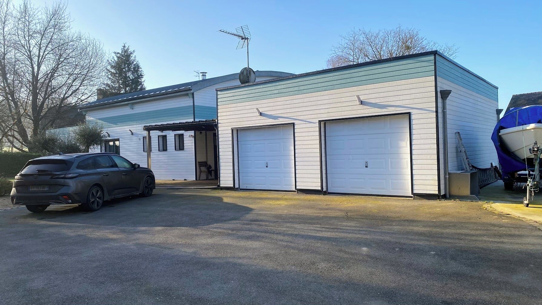 Un bâtiment à deux étages avec un garage, une allée couverte et un VUS garé.