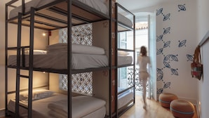 A bunk bed room with a number on each bunk, a patterned wall, and a window with a view.