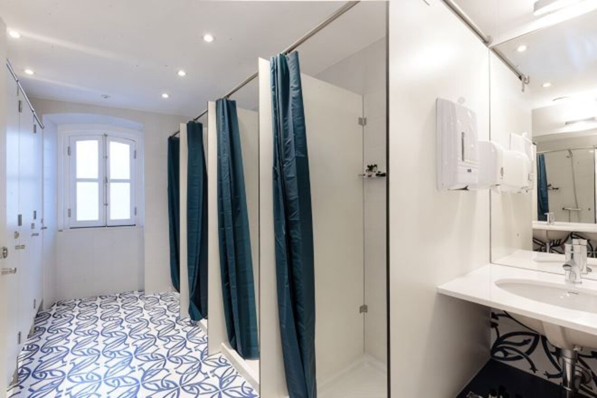A bathroom with a shower, a sink, a mirror, and a patterned floor.