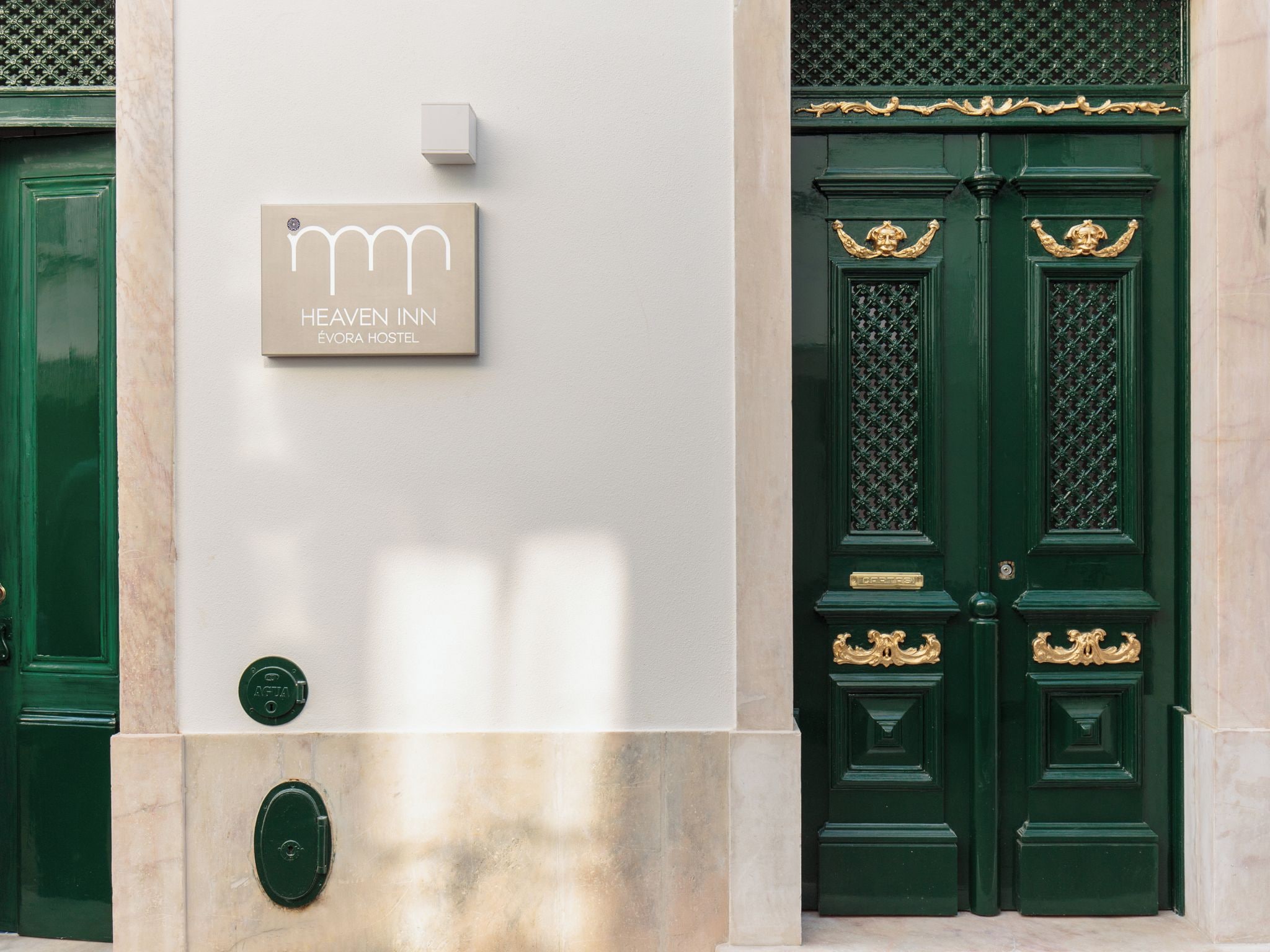 A hotel entrance with a sign reading 'HEAVEN INN ÉVORA HOSTEL.'