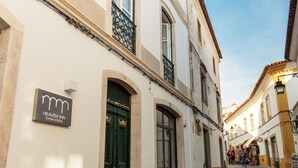 A street view with a building labeled 'Heaven Inn Évora Hostel' featuring a cobblestone street, traditional architecture, and a clear sky. - Heaven Inn Suites & Terrace (Évora)