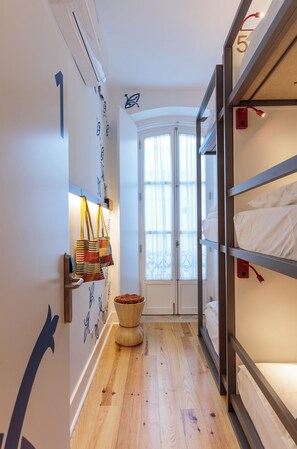 A narrow hallway with bunk beds on one side, a door with a frosted glass panel, and a wall-mounted air conditioning unit. - Heaven Inn Suites & Terrace (Évora)