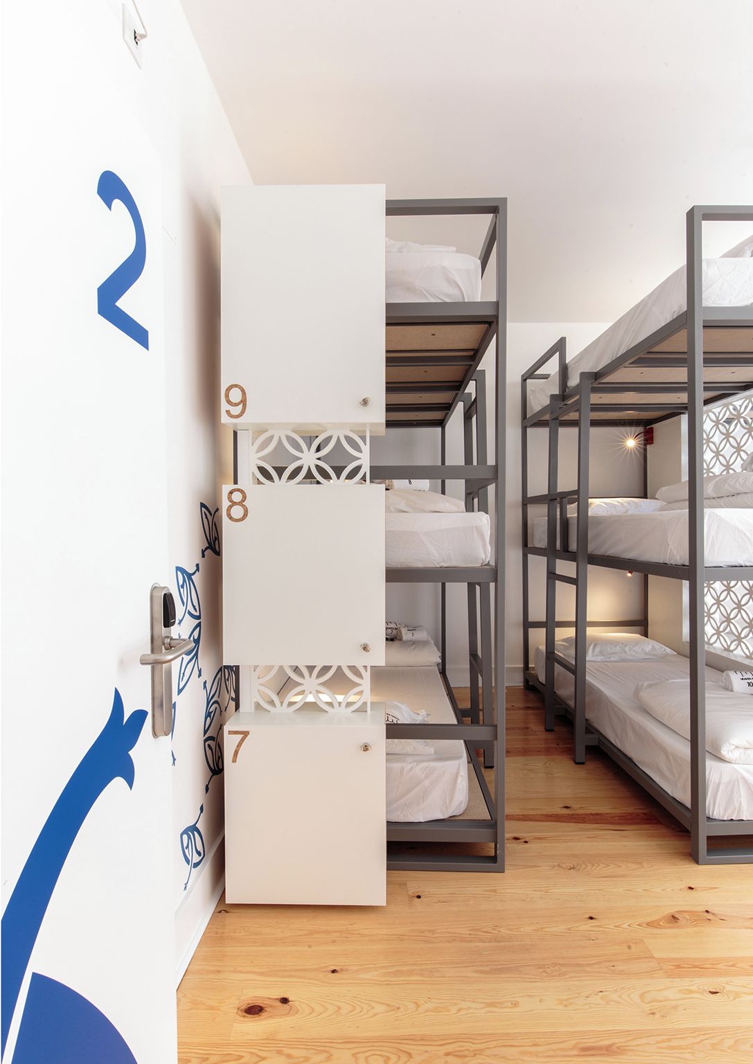 Un dormitorio con literas, puertas numeradas y suelo de madera.