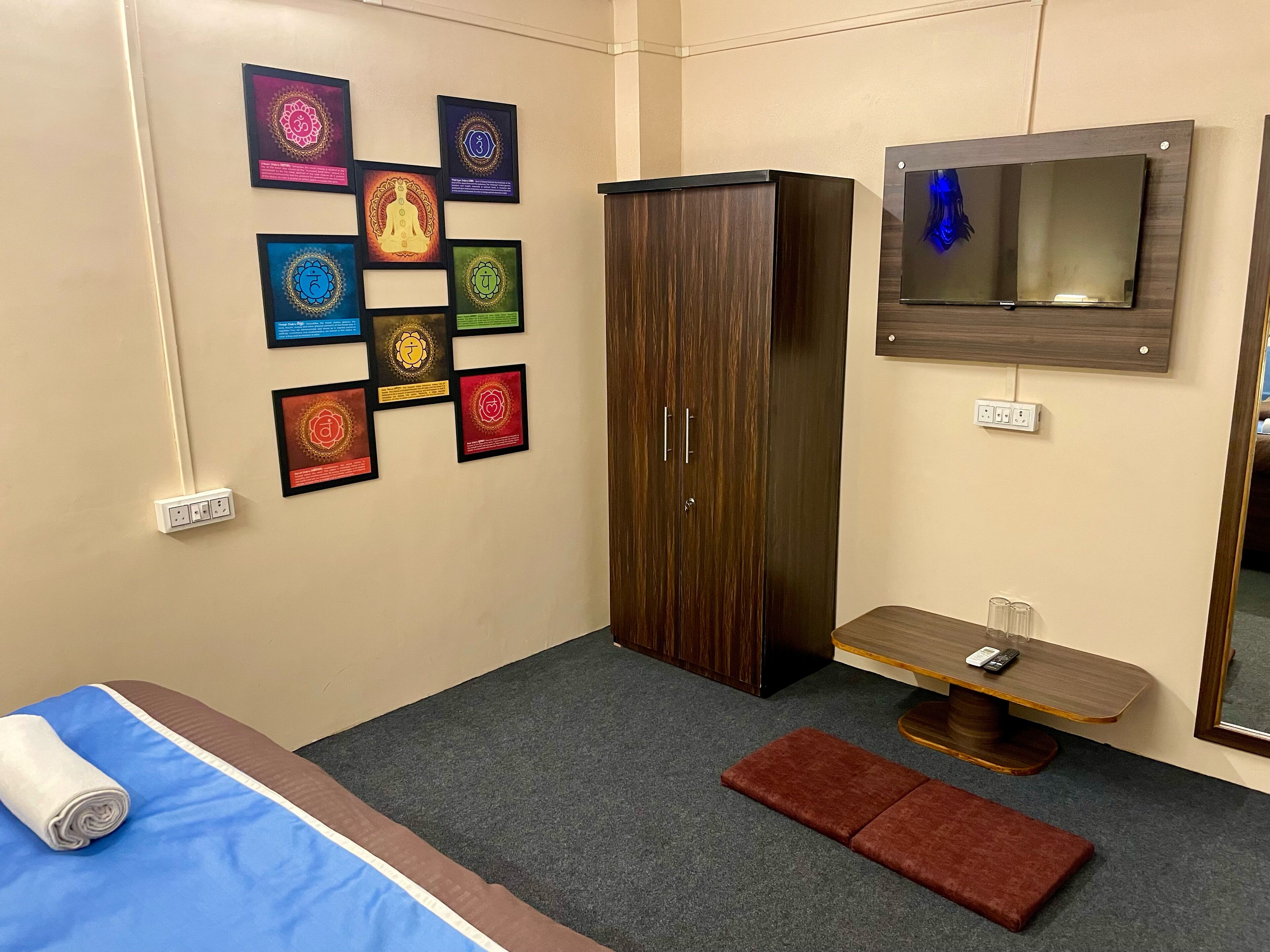 Un dormitorio con una cama, un armario, una mesita con espejo y una pared decorada con cuadros.