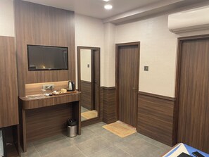 Ein modernes Badezimmer mit einem Holz-Waschtisch, einem Spiegel, einem Fernseher und einem Mülleimer.