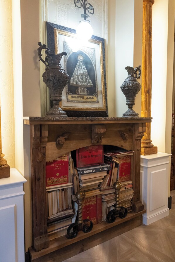 Une cheminée surmontée d’un tableau encadré, entourée de livres et de vases décoratifs.