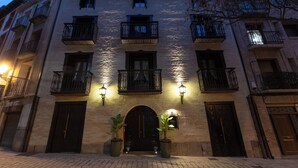 A multi-story building with a brick facade, arched entrance, and multiple balconies. - 5 Sentidos - Suites de Lujo (Tudela)