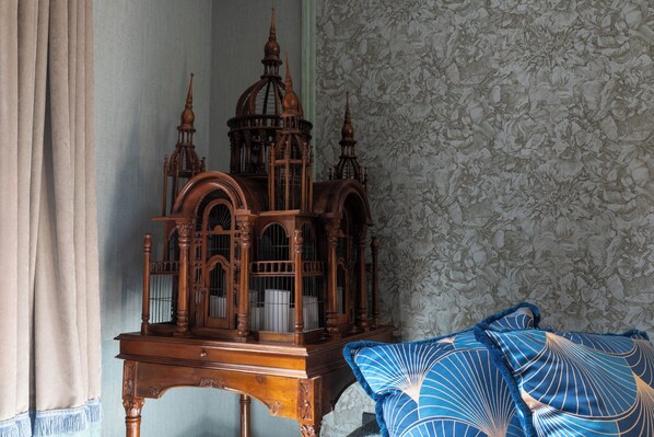 A room with a wooden cabinet, a patterned wallpaper, and a blue patterned pillow. - 5 Sentidos - Suites de Lujo (Tudela)