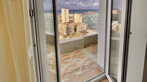 En balkon med udsigt over byen, flisegulv og en skydedør.