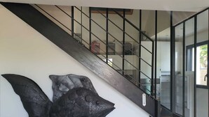 A modern staircase with a glass railing and a unique black wall art piece.