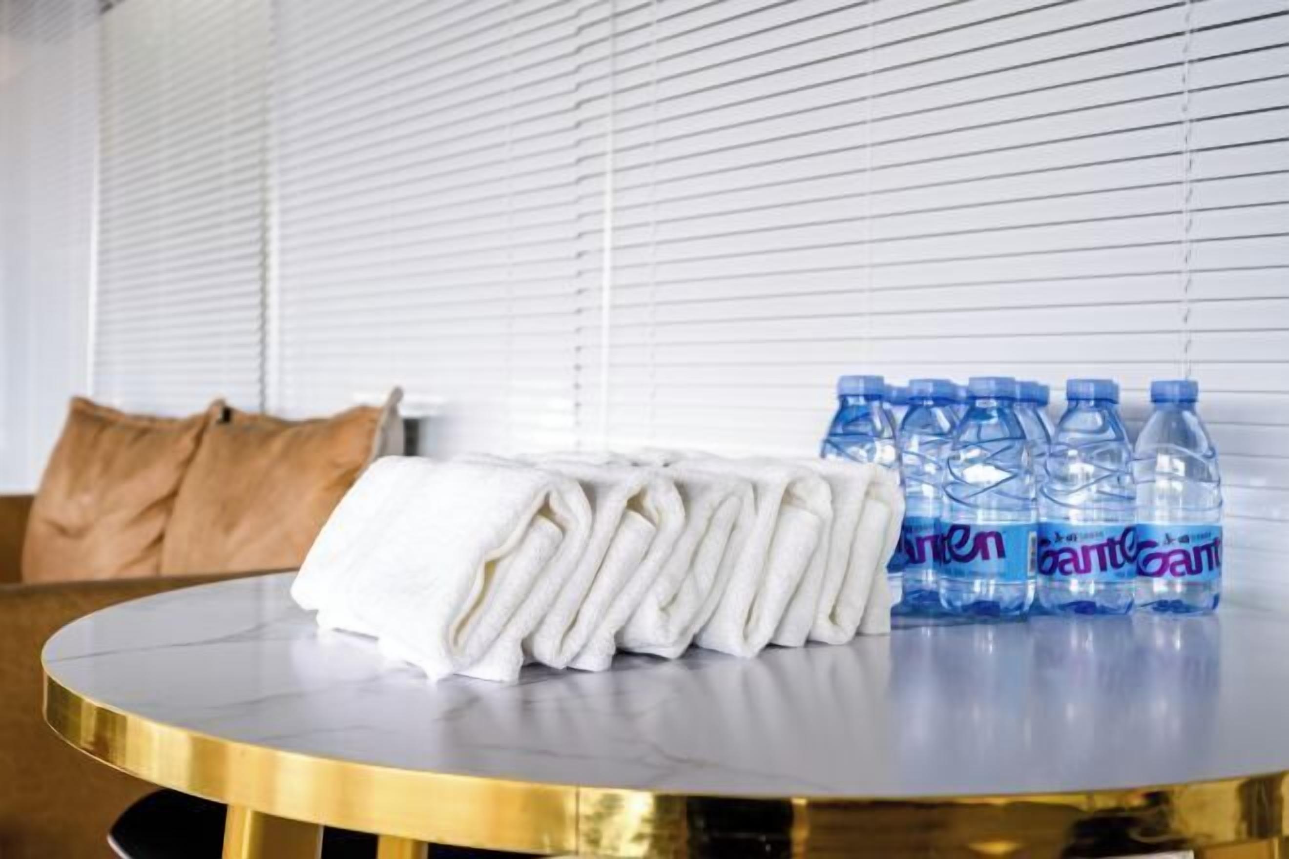 Een ronde tafel met keurig opgevouwen witte handdoeken en verschillende waterflessen.